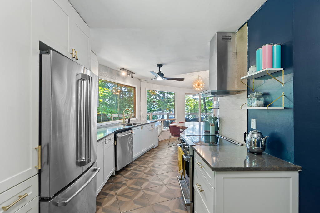 A narrow kitchen with updated appliances curves toward a dining area.