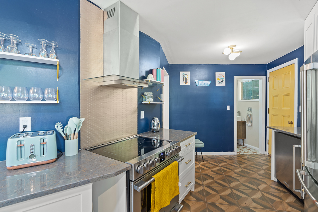 A narrow, curving kitchen with updated appliances, just off the front entrance of a cottage.