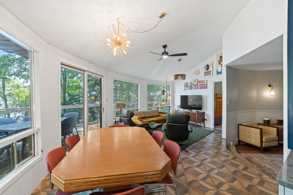 A dining area with a table and chairs sits in front of a wall of windows.