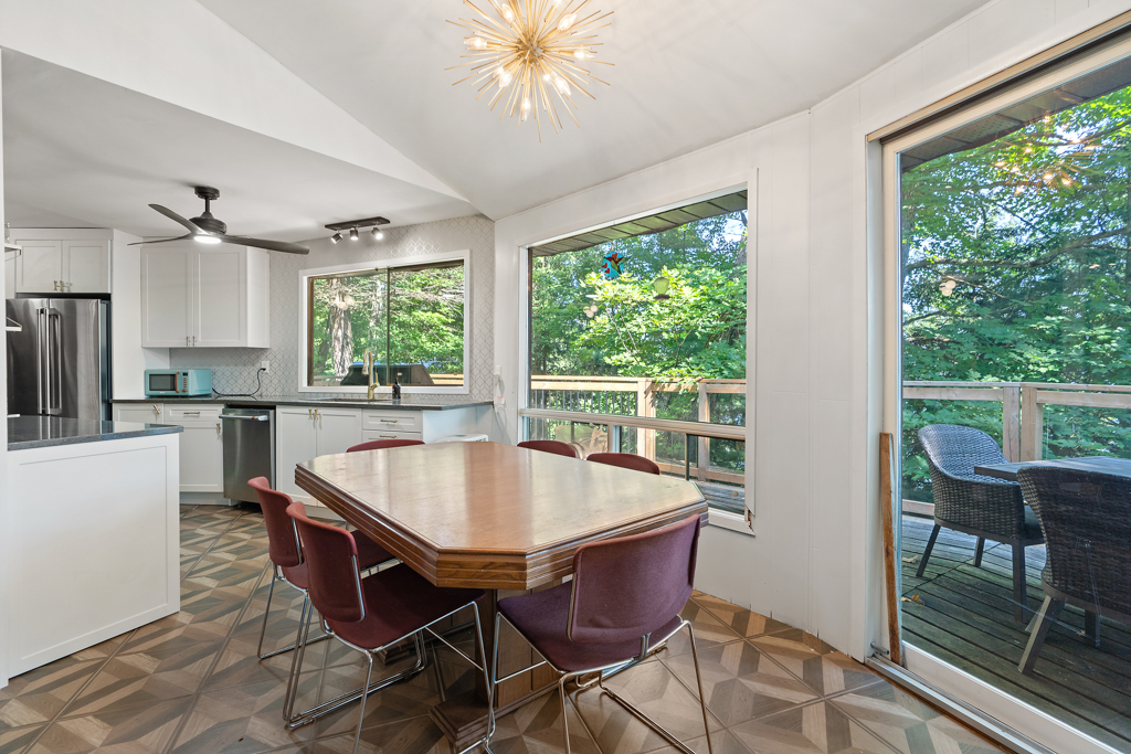 A dining area with a table and chairs sits in front of a wall of windows.