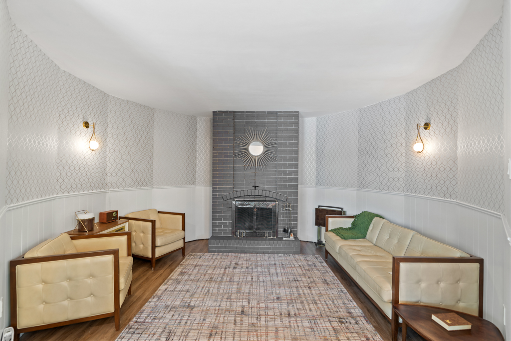 A large, sunken den with a couch, chairs, and a wood-burning fireplace.