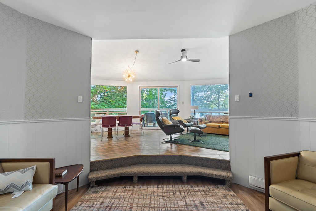 Two steps lead up out of a sunken den into a bright living area.