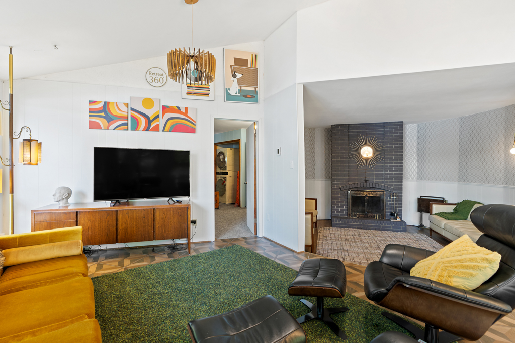 A bright living area with a television leads down into a sunken den with a fireplace.