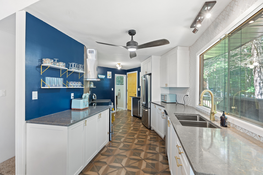A narrow, bright kitchen with updated appliances curves through a cottage.