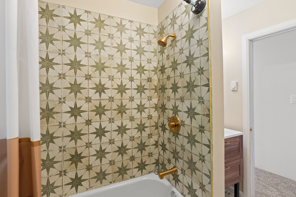A bathroom with a shower-tub combo that as retro-style tile.