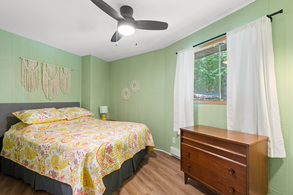 A bedroom with light green walls, a large bed, and a dresser.