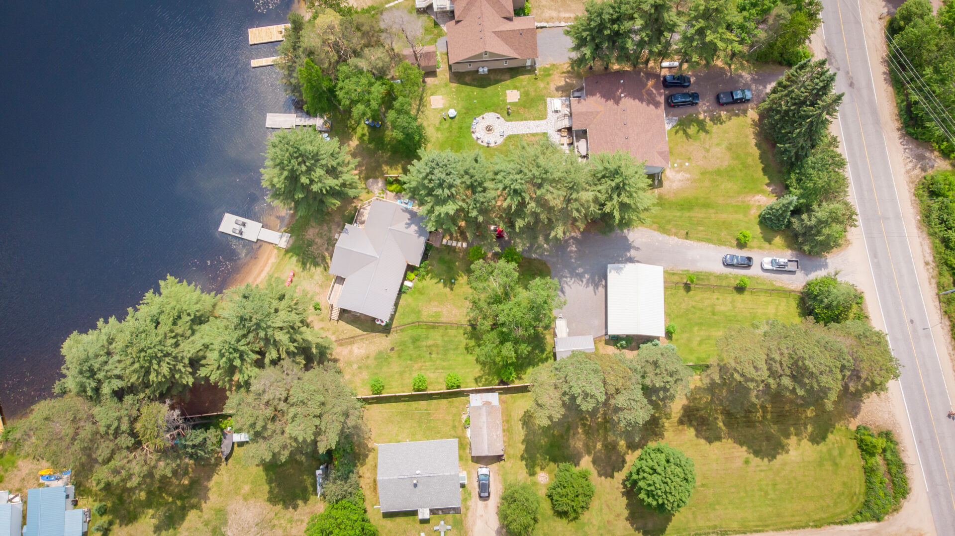 Aerial view of a cottage bungalow sitting just up the shore from a lake.