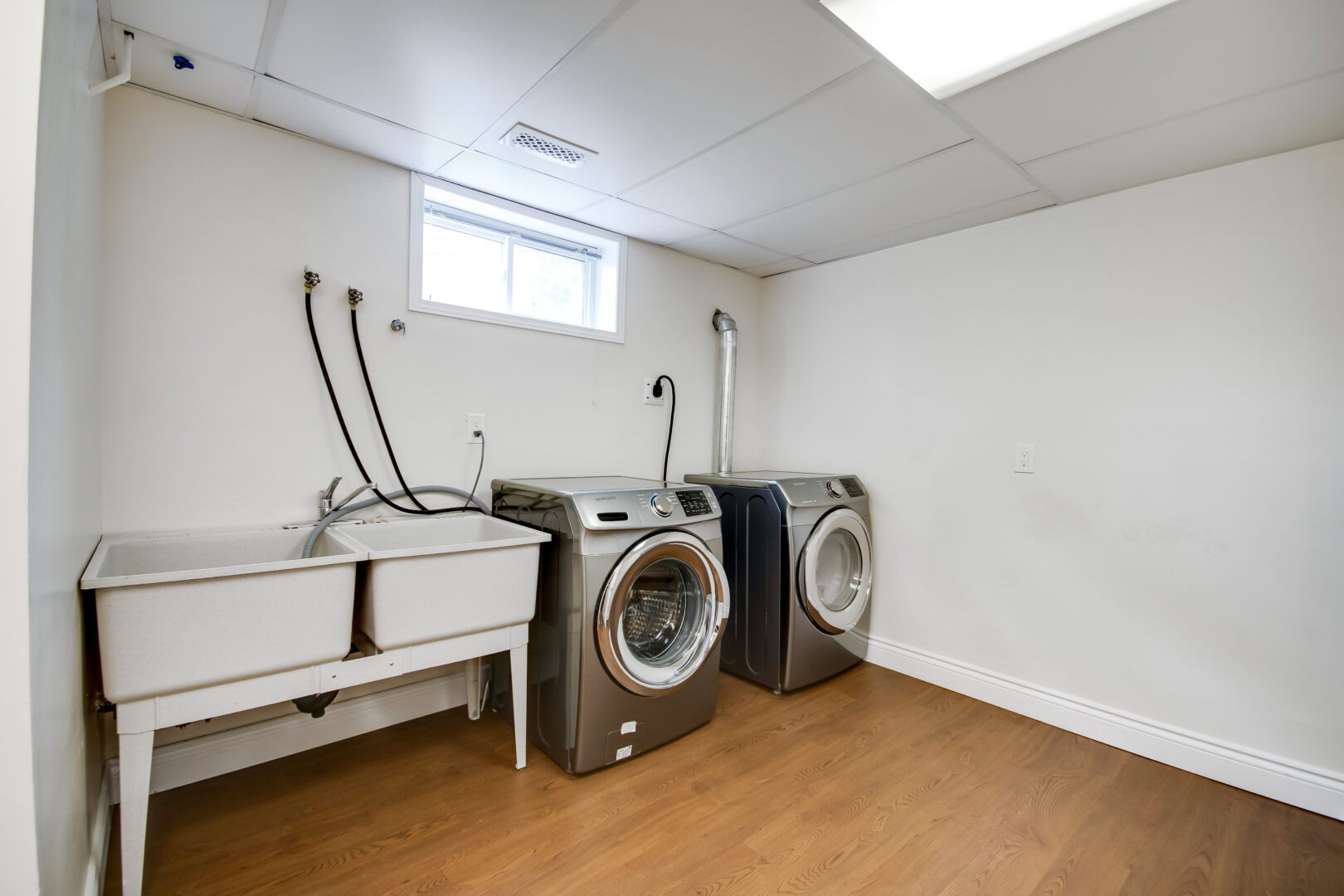 A lower level laundry area with a washing machine, a dryer, and two sinks.