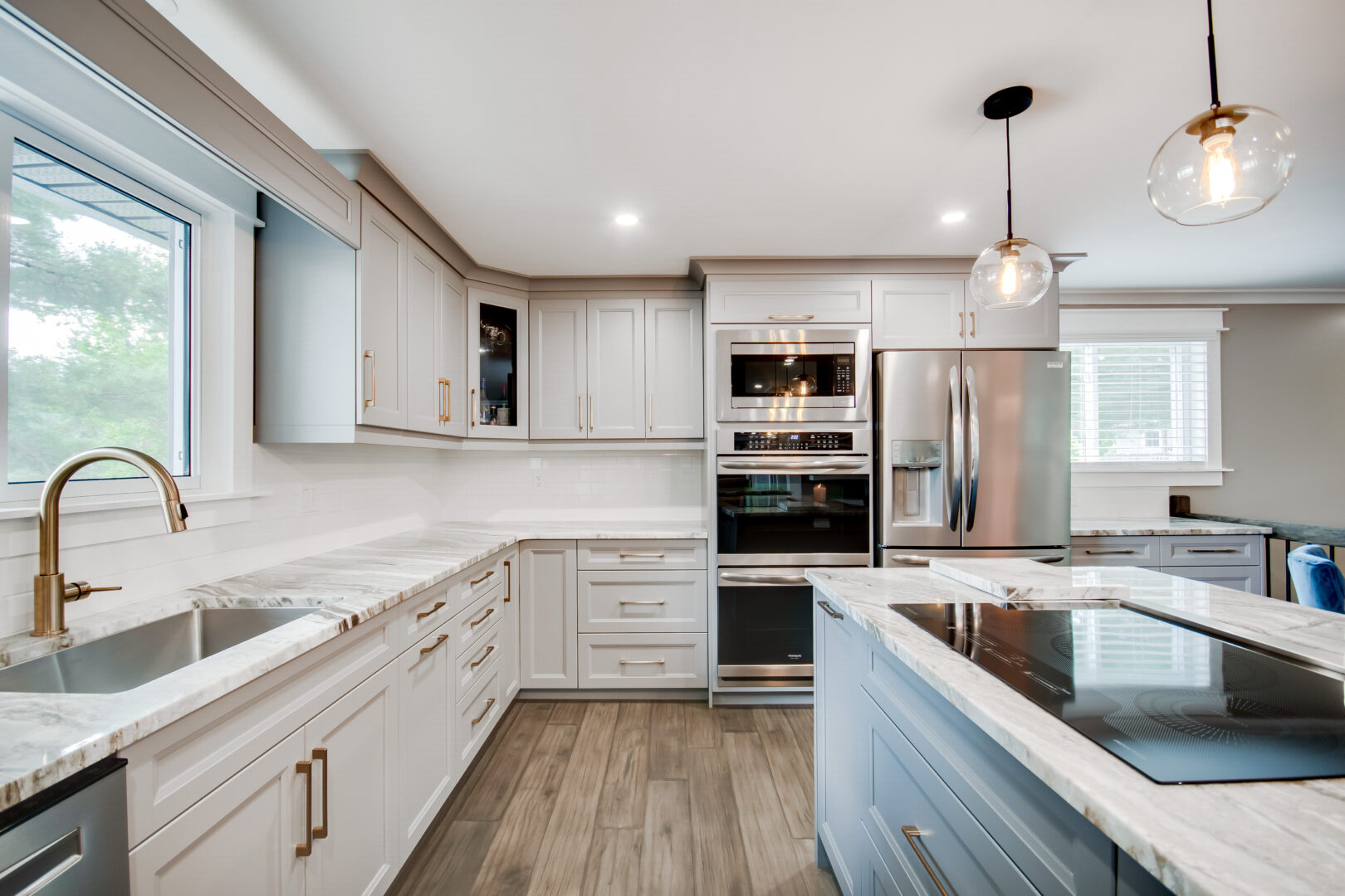 An updated, modern kitchen with new appliances, white cupboards and countertops, and a pale blue island.