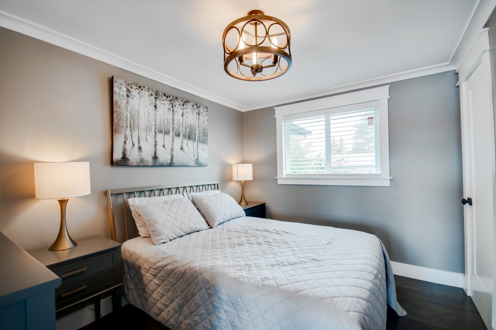 A bright bedroom with a double bed and a metal light fixture.