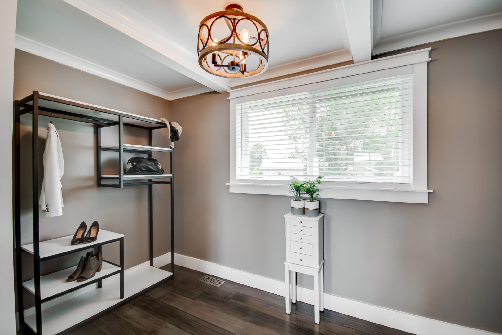 A large walk-in closet area of a primary bedroom, with a window inside.