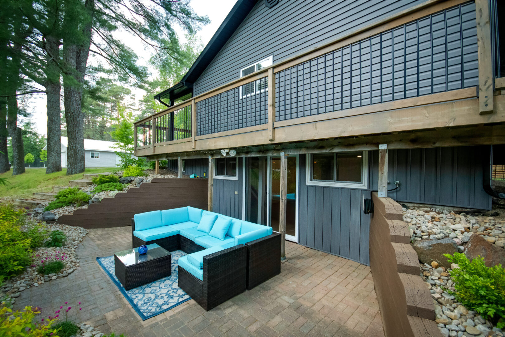 A patio extends from a lower-level walk-out of a cottage bungalow.