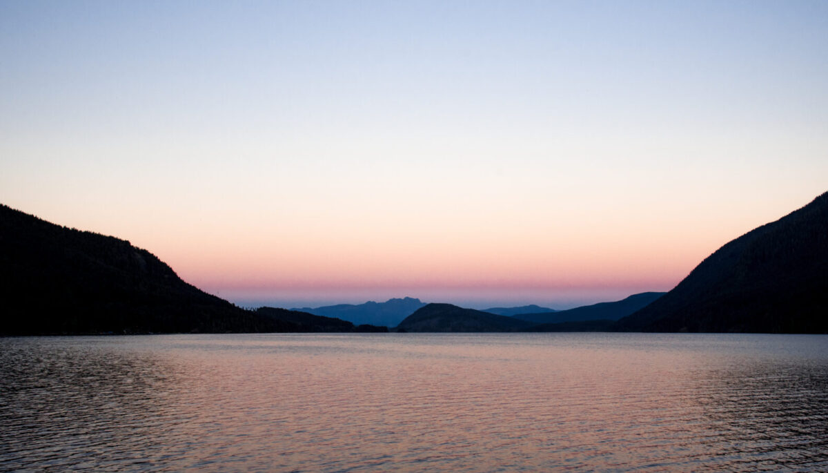 Scenic view of Sproat Lake and mountains at sunset
