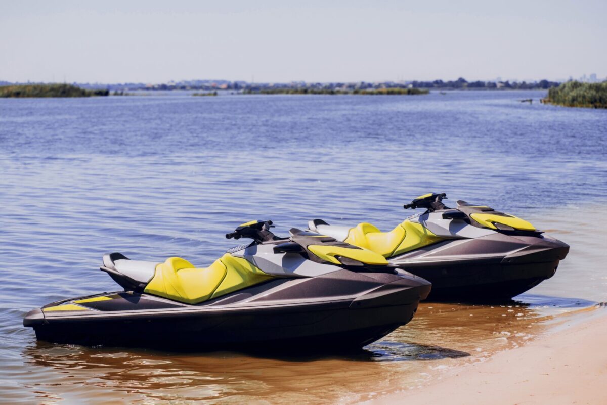 Two jetskis (PWCs) sitting on a beach shore