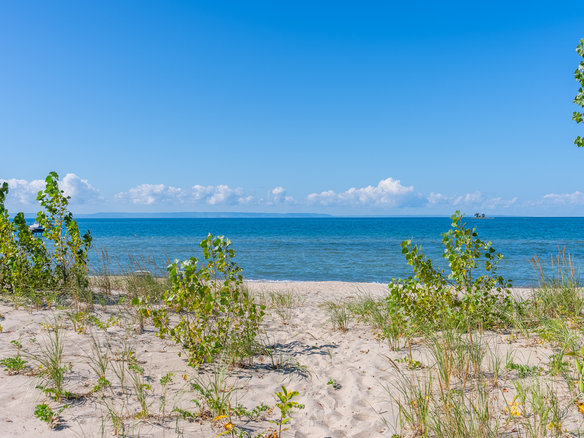 A sandy beach in front of blue water.
