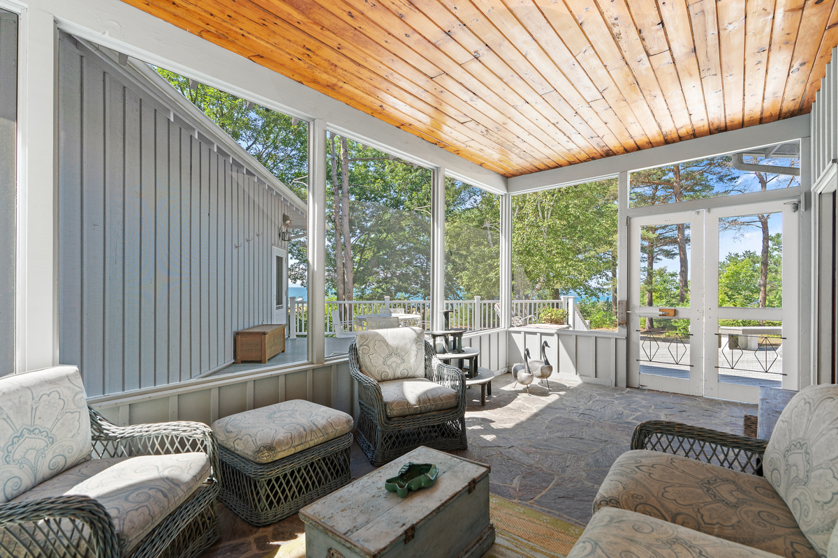 A bright sunroom with lots of seating and a wood-panelled ceiling.