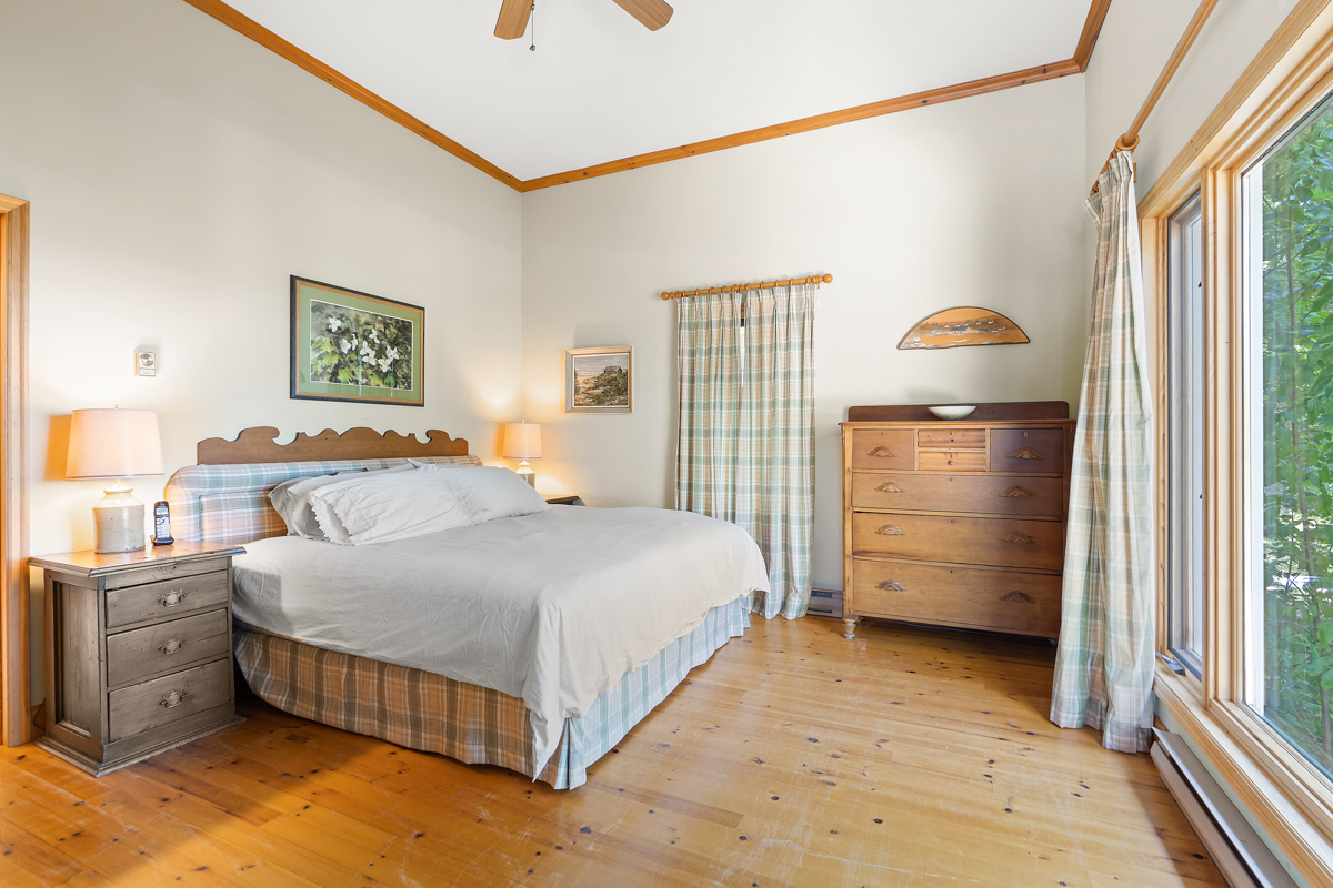 A large, bright bedroom with a big bed and plaid curtains.