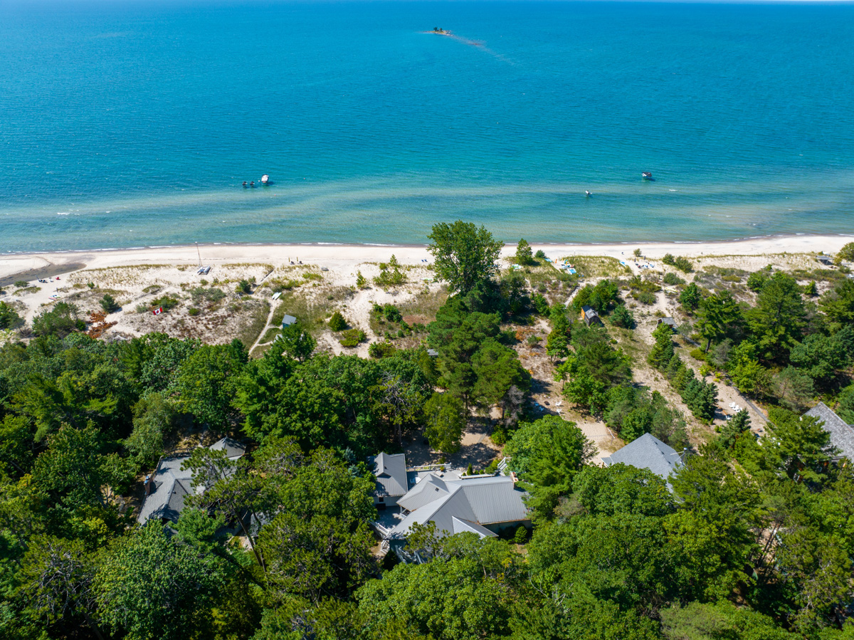 Cottages line a beachy waterfront on a blue lake.