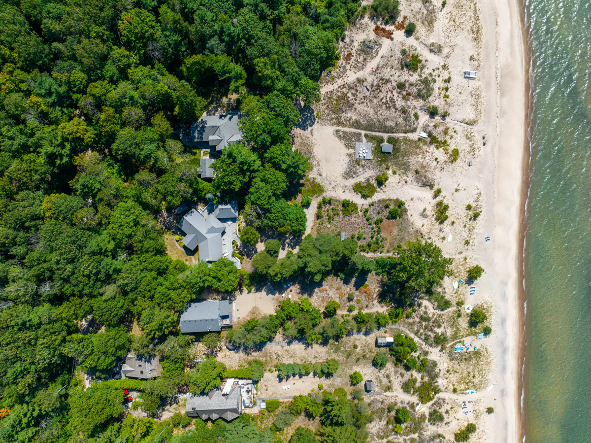 Overhead view of a beachy waterfront lined with large cottages.