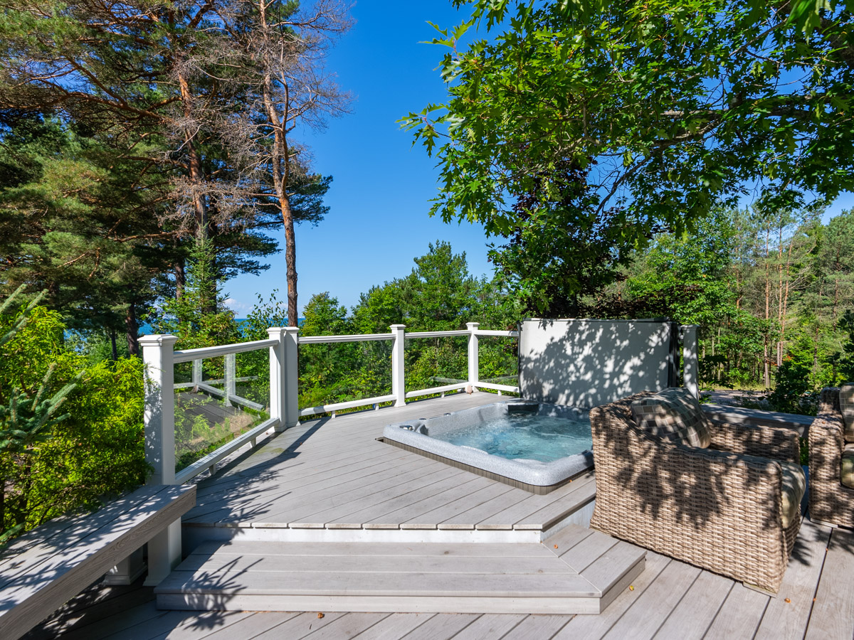 Steps on a back deck lead to a raised area with a built-in hot tub.