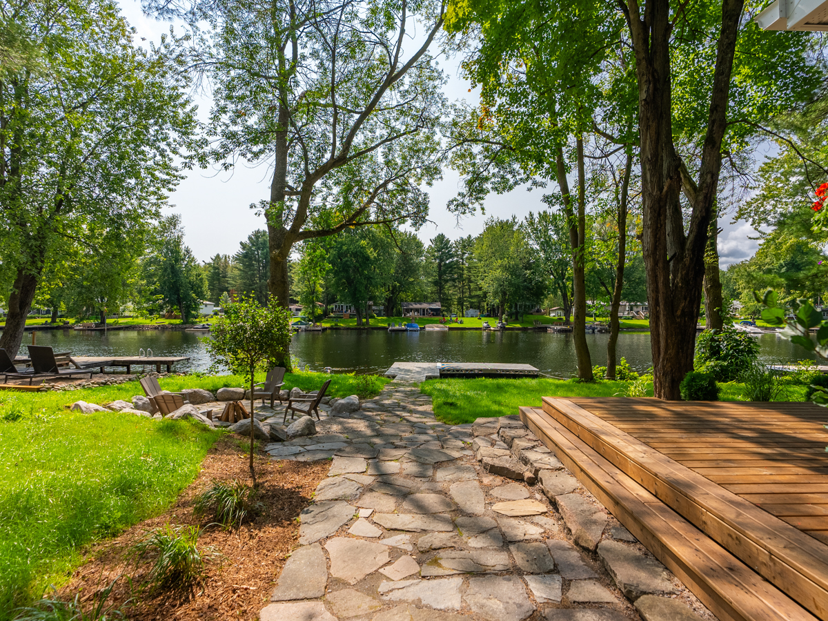 A patio walkway leading to a fire pit and a dock.