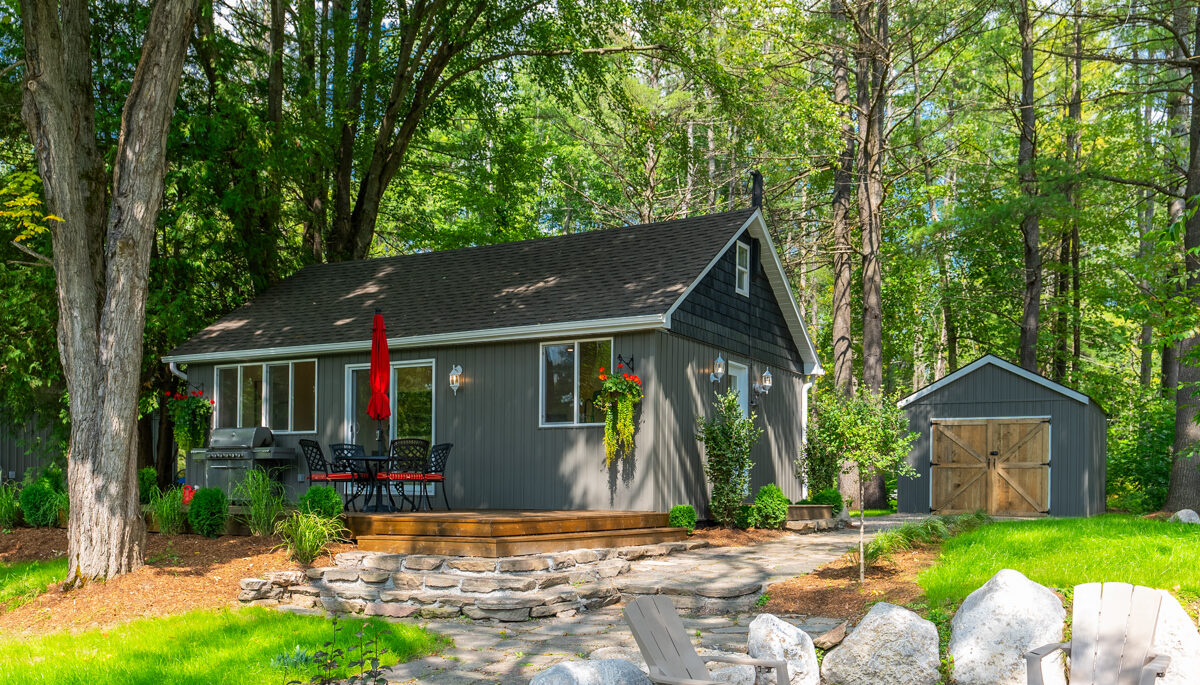 A fire pit. A cottage sits across a wide grassy yard.