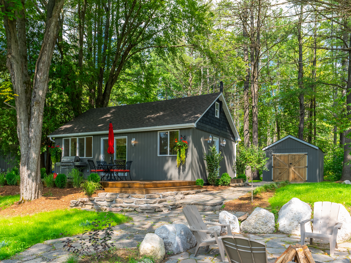 A fire pit. A cottage sits across a wide grassy yard.
