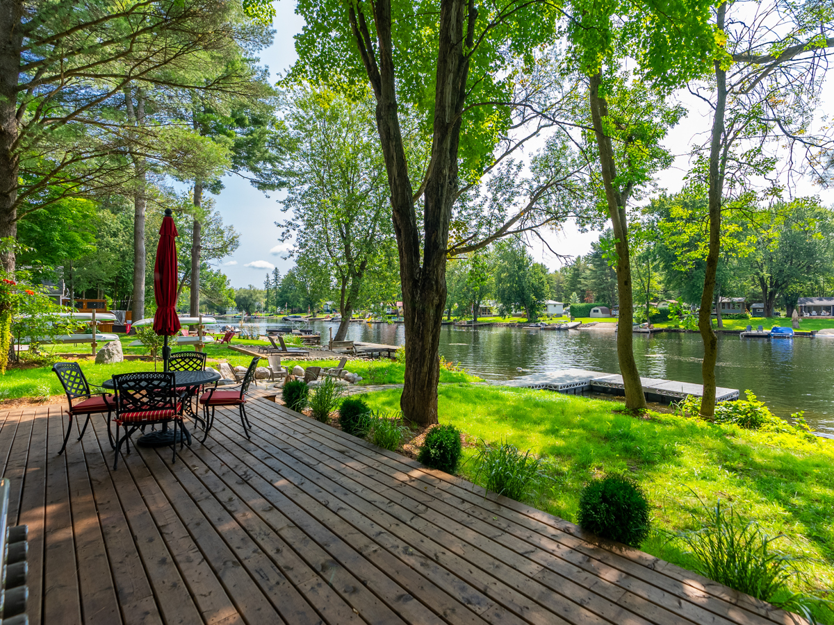 A large deck with patio dining furniture extending off a cottage.