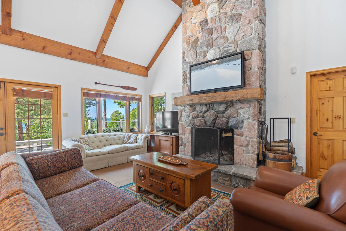 A bright cottage living area with high ceilings, a floor-to-ceiling fireplace, and lots of seating.