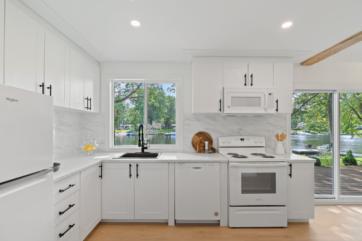 A bright cottage kitchen with white cupboards and appliances.