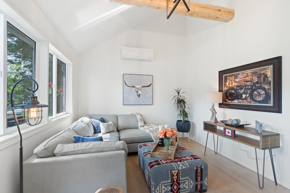 A cottage living area with a vaulted ceiling, a large couch, a coffee table, and a television.