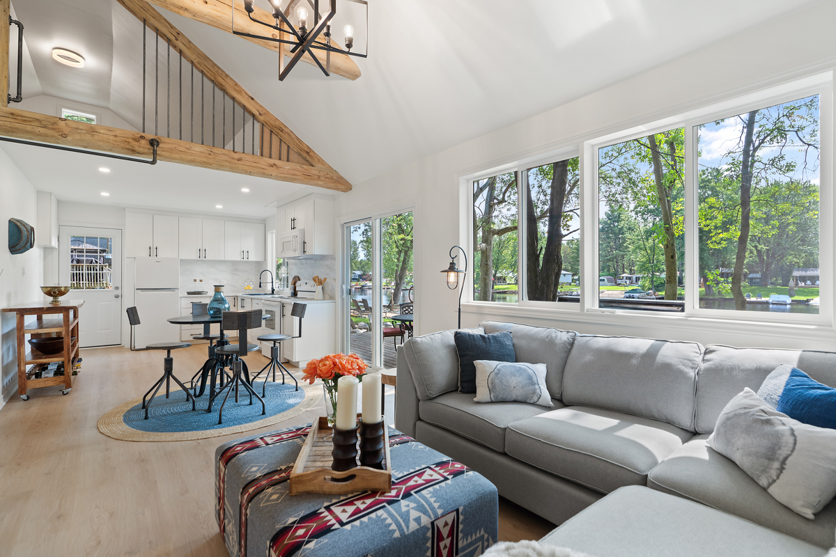 A bright cottage living space with a grey couch and a high ceiling.