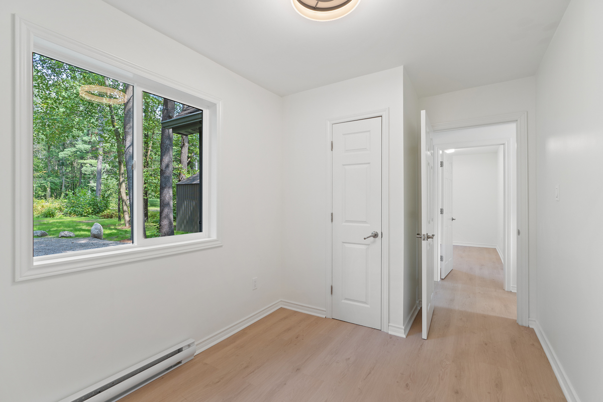 An empty bedroom with hardwood floors and white walls.