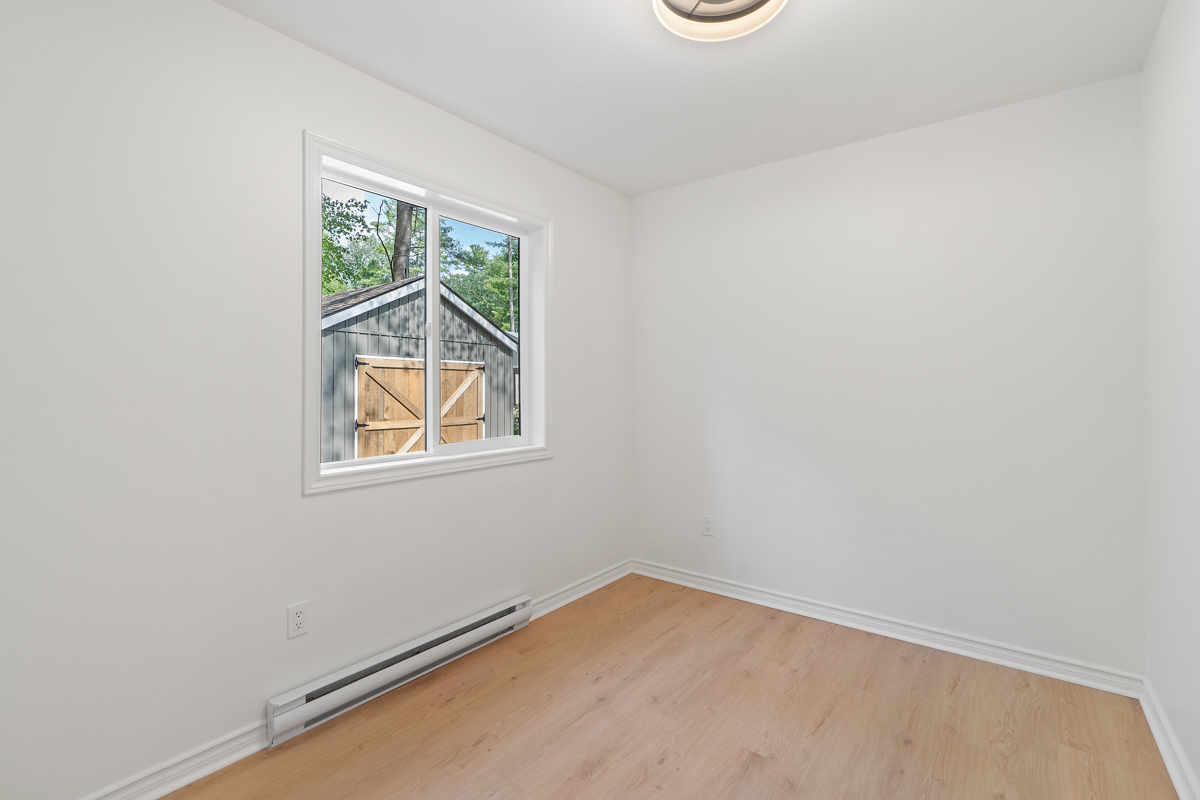 An empty bedroom with hardwood floors and white walls.