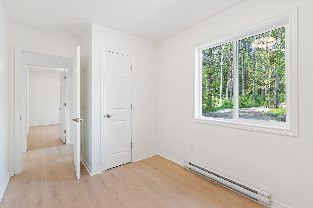 An empty bedroom with hardwood floors and white walls.