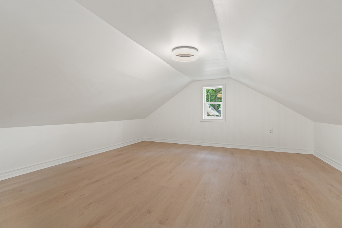 A wide, empty loft space with hardwood floors and white walls.
