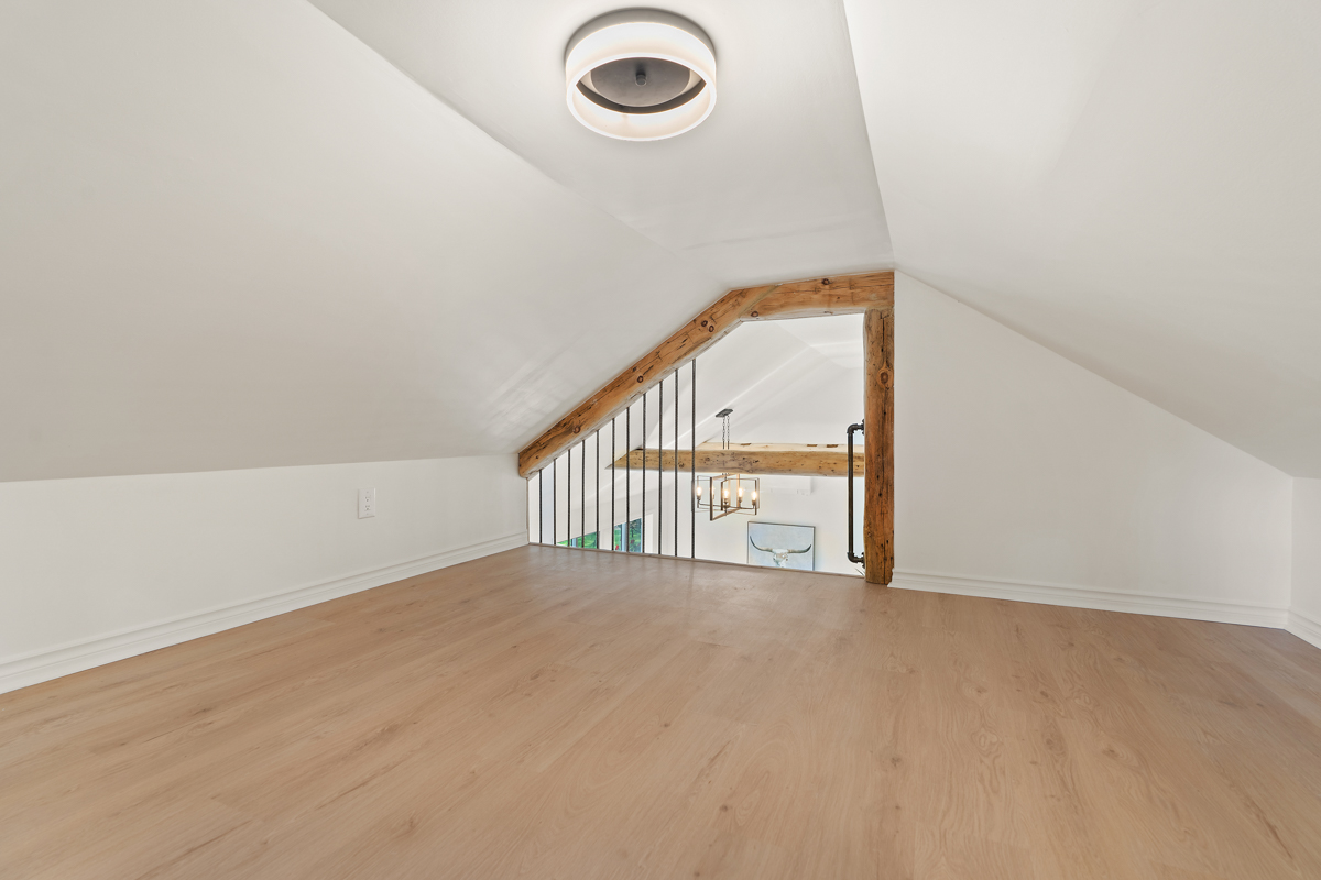 A wide, empty loft space with hardwood floors and white walls.