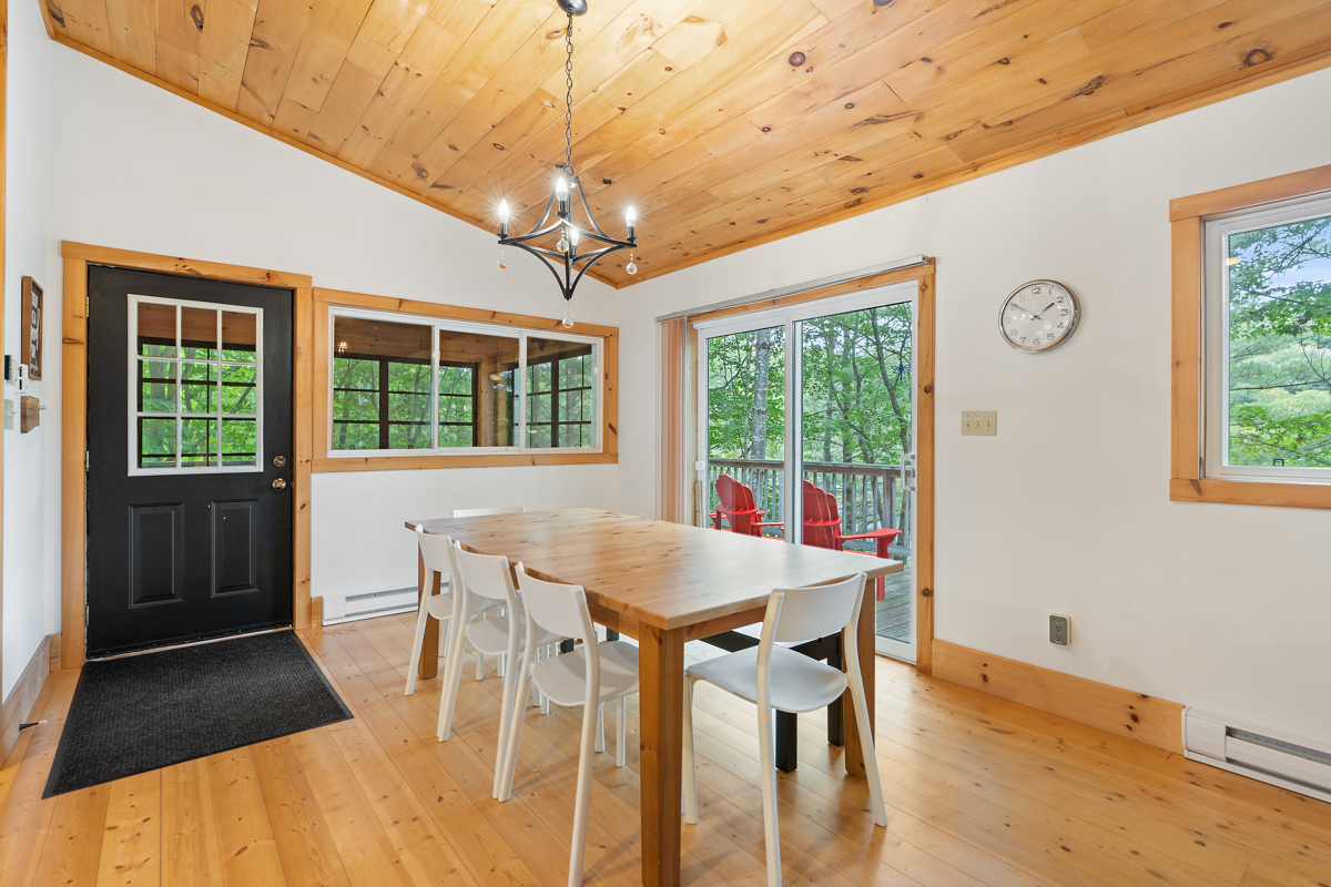 A main floor dining area with wood-panelled ceilings and a table and chairs.