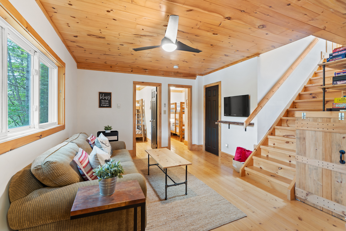 A small lower-level living area at the bottom of a staircase, with a couch and a television.