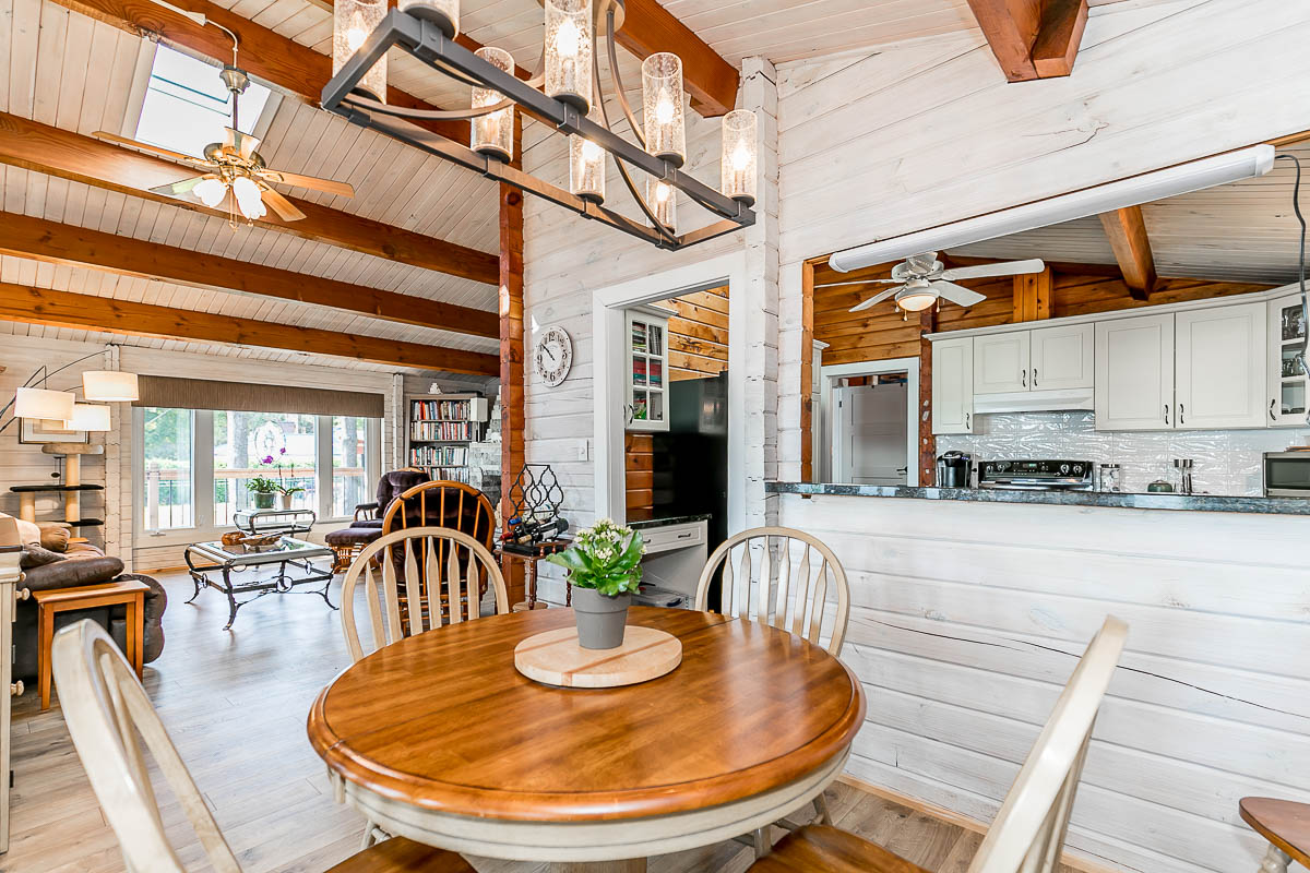 A small, round table and chairs. The dining area flows into a kitchen and living area.
