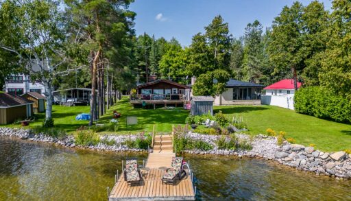 A cottage property sits on the edge of a lake. A big dock extends into the water.