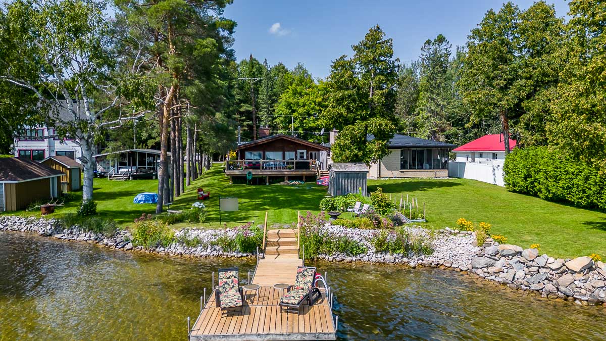 A cottage property sits on the edge of a lake. A big dock extends into the water.