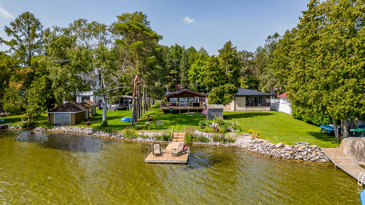 A cottage property sits on the edge of a lake. A big dock extends into the water.
