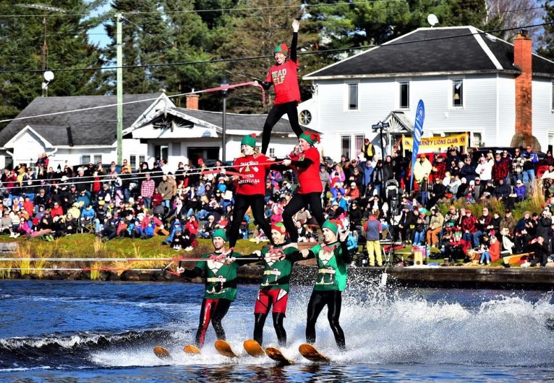 A group of people waterski in a tower formation