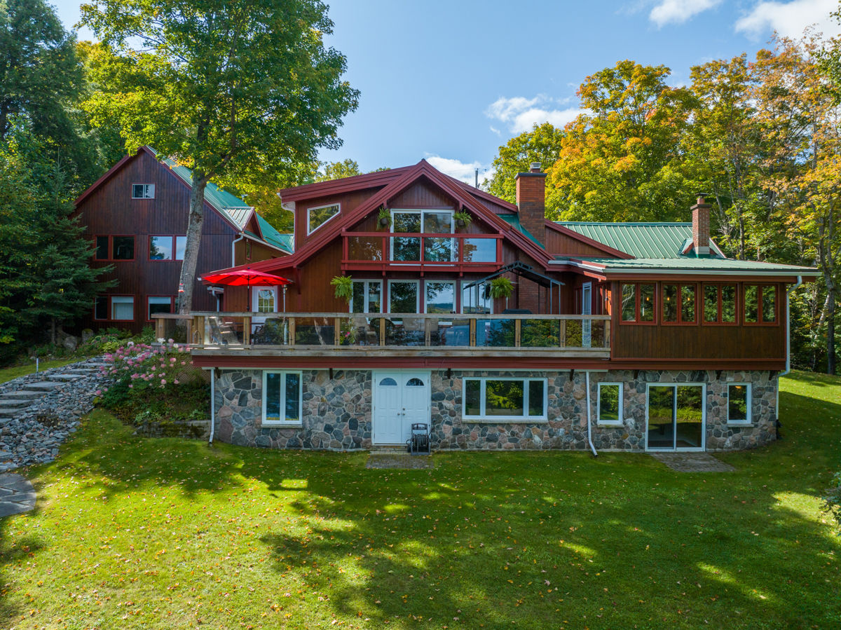 Exterior of a large cottage with a big grassy area and a deck spanning the length of the building.