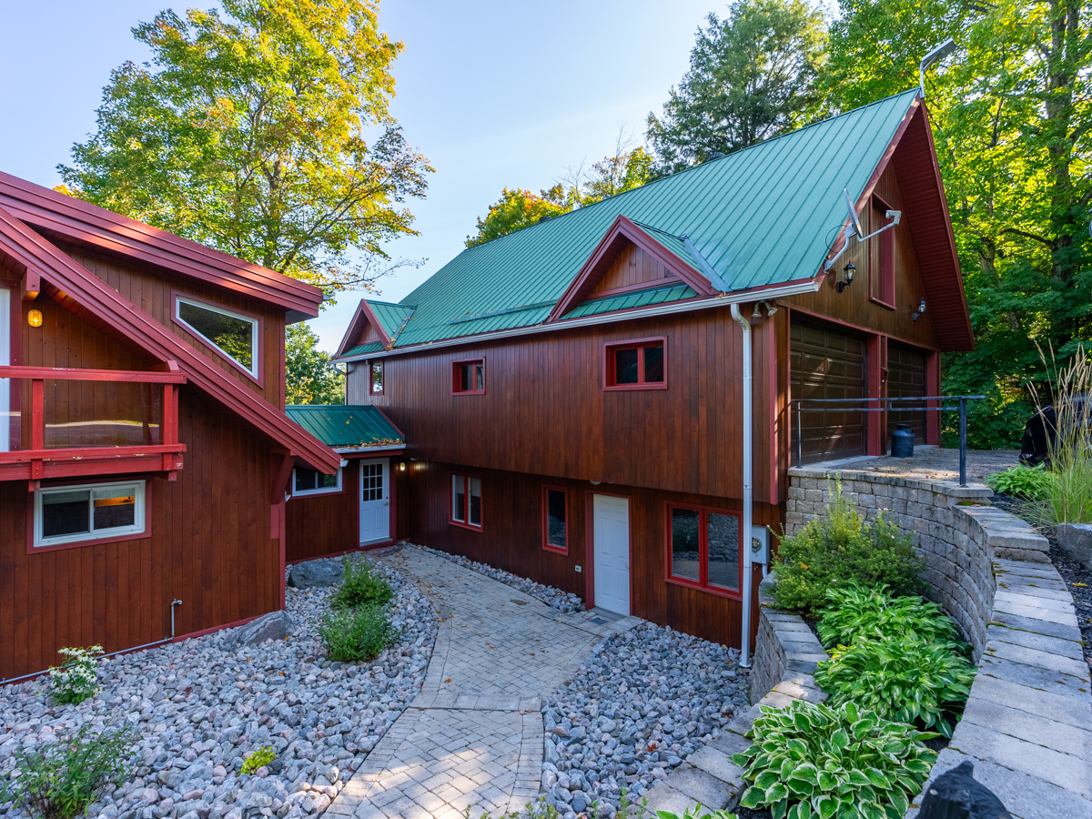 A garage extends off the side of a cottage with a green roof.