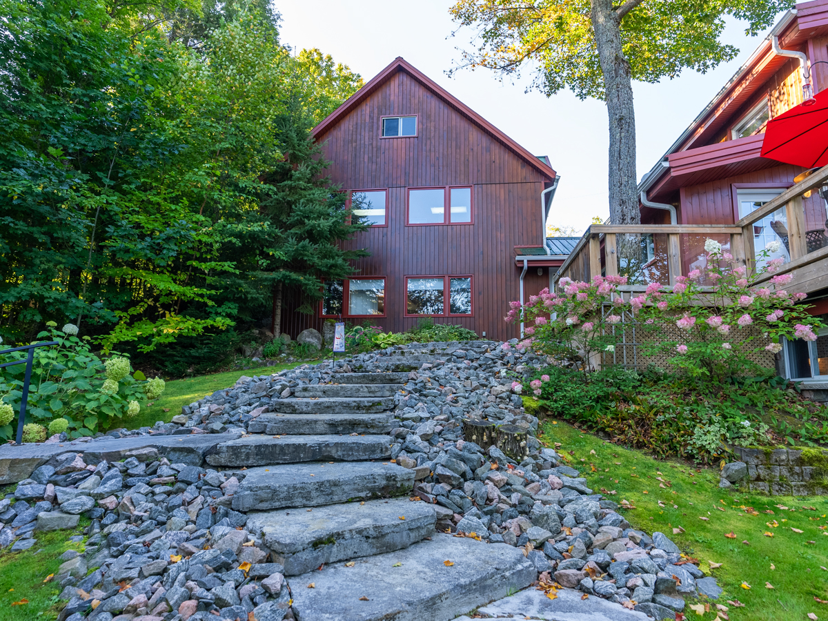 Stone steps lead up from a grassy area to a big cottage.