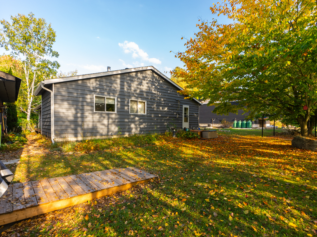 Large, grassy backyard behind a cottage bungalow.