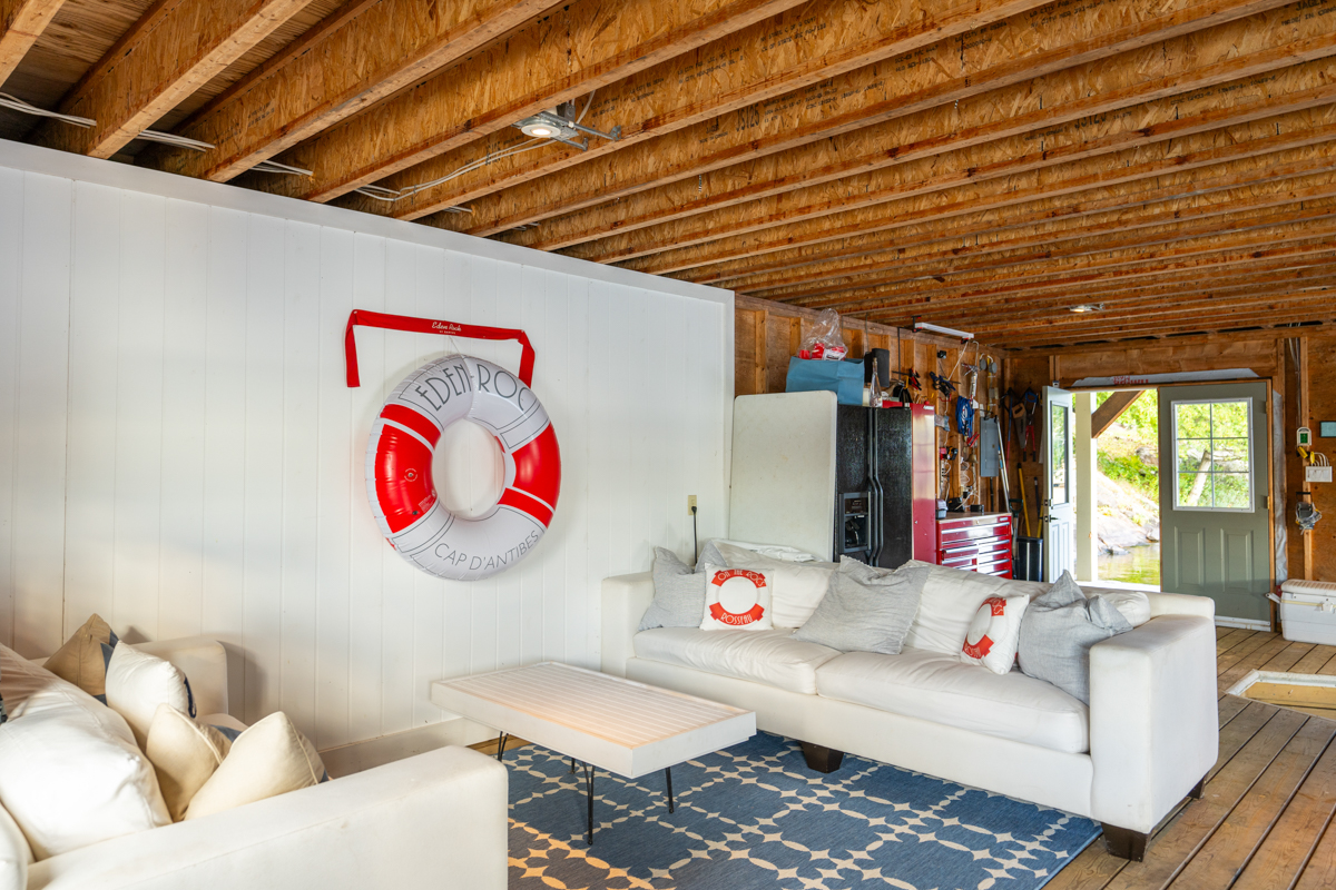 Two white couches create a small living area inside a big boathouse.