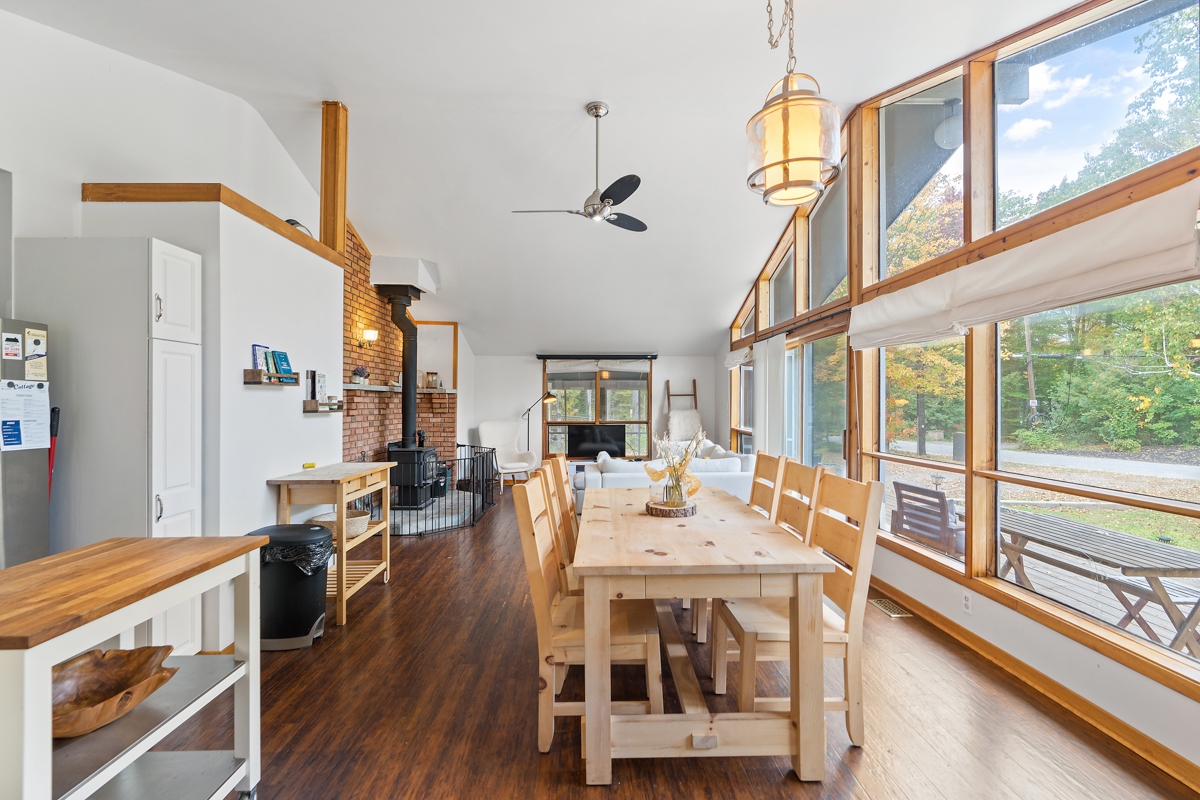 A main floor bungalow space that flows from the dining area to the living area. Floor-to-ceiling windows span the front wall of the house.